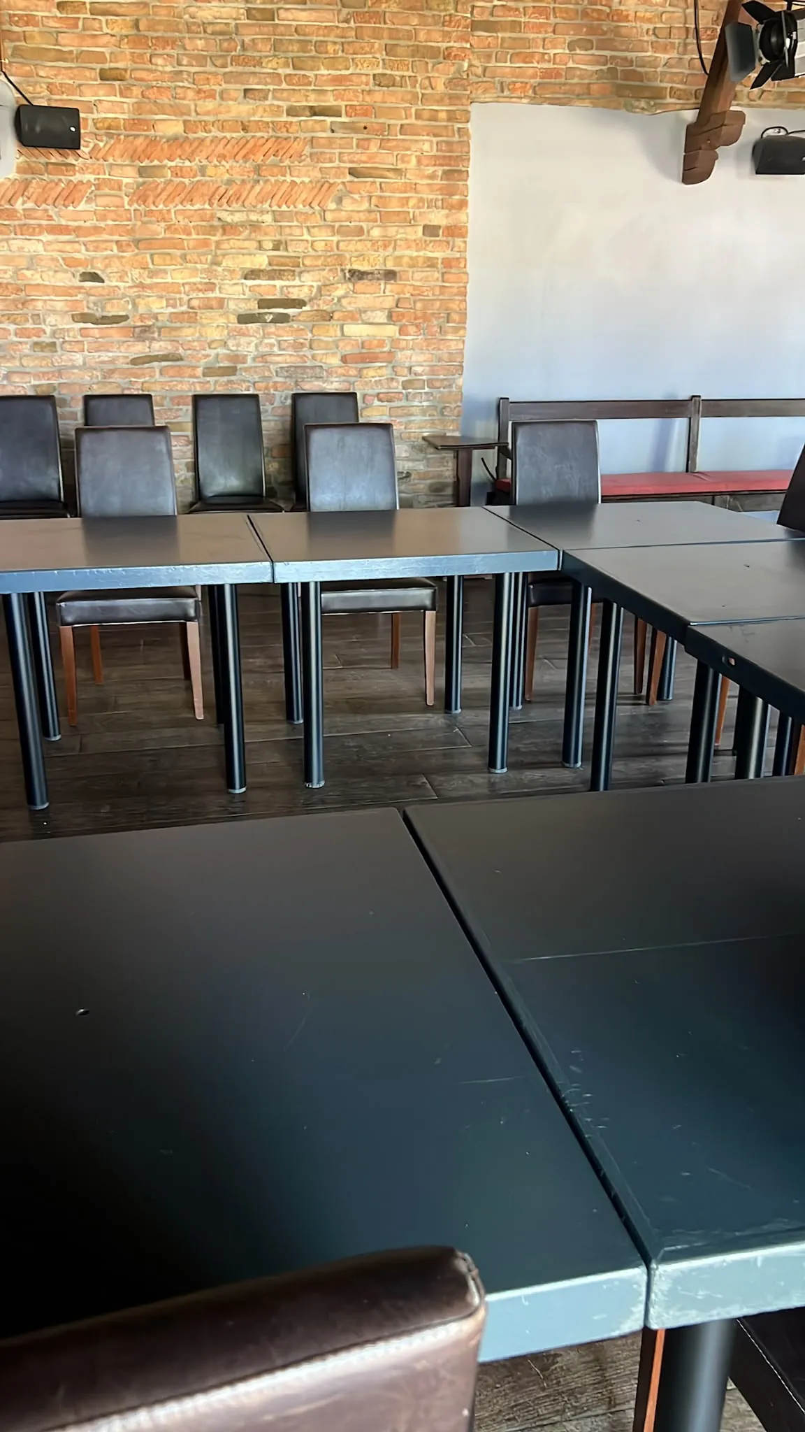 La sala del ristorante con parete in mattoni a vista e tavoli apparecchiati
