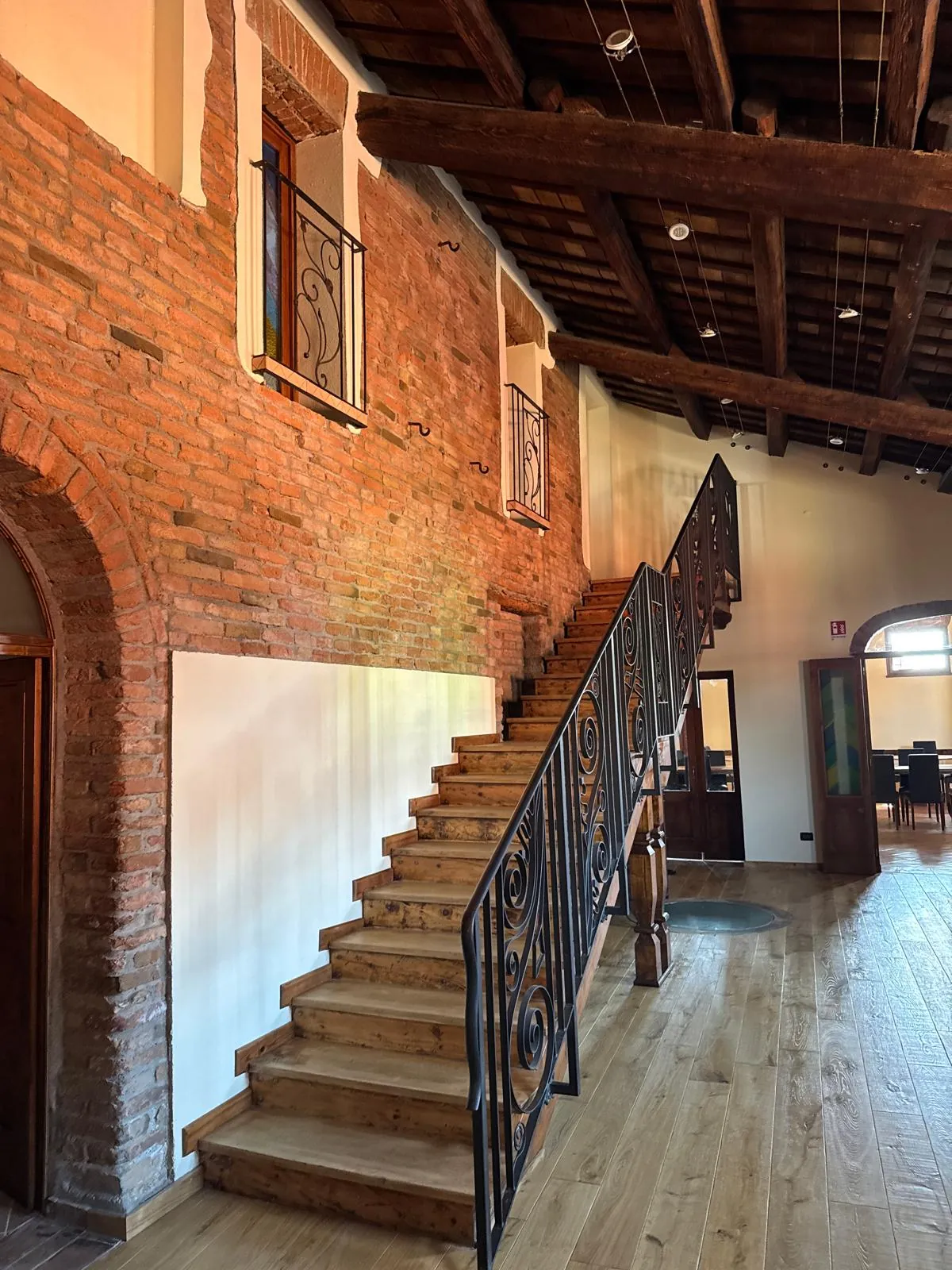 La scala in ferro battuto che sale alla Torre, tra mattoni a vista e travi