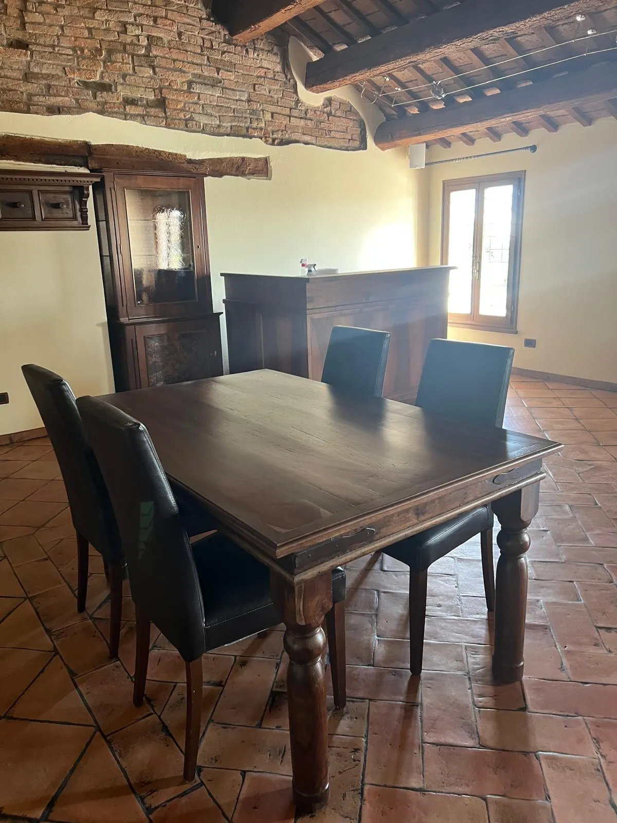 Tavolo in legno massello nella sala con travi e mattoni a vista